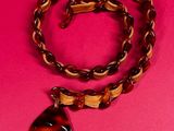 a brown necklace with a brown and black pendant on a pink background