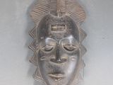 un masque en bois accroché au mur d'une pièce