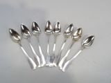 six silver spoons are arranged in a circle on a white surface