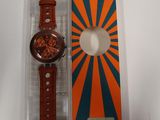 une montre orange et bleue posée sur une boîte blanche
