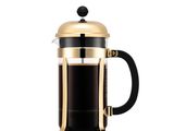 une cafetière à piston dorée et noire sur fond blanc