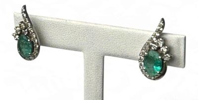 une photo d'une paire de boucles d'oreilles en émeraude et diamant posées sur un présentoir