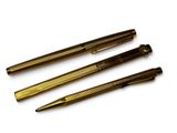 trois types de stylos différents sont alignés sur une surface blanche