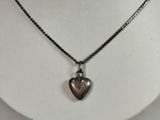 silver heart pendant on a black chain on a white mannequin