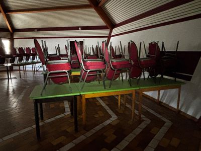 de nombreuses chaises et tables dans une pièce au sol en parquet