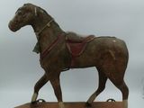 un cheval en bois muni d'une selle, posé sur un skateboard
