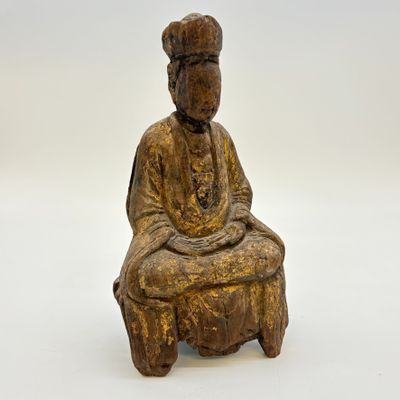 statue en bois représentant un homme assis sur un tabouret, les mains croisées