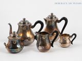 four pieces of silver tea and coffee set on a white surface