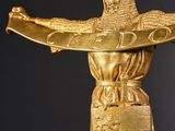 a gold statue of a man holding a cross on top of a table