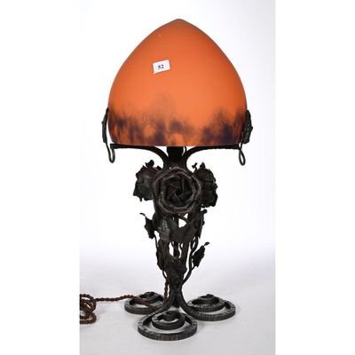 an orange glass lamp with a metal base and flowers on it