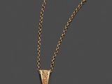 un pendentif en forme de croix en or, suspendu à une chaîne, sur fond gris