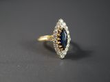 gros plan d'une bague en or avec un saphir et des diamants