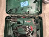 a green box with a cord and a drill in it