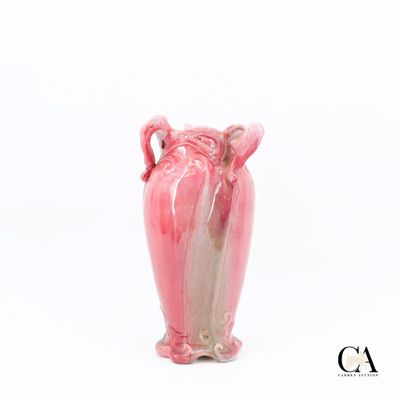 un vase rose à deux anses posé sur une surface blanche