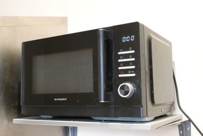 a microwave sitting on top of a shelf with a clock on it