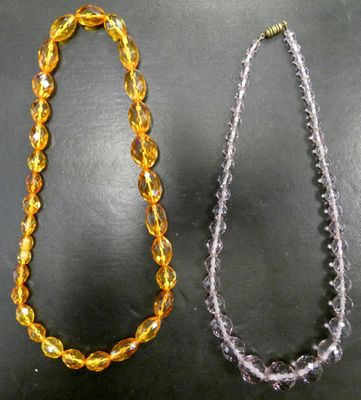 deux colliers de couleurs et de tailles différentes posés sur un fond noir