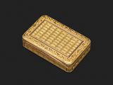 une petite boîte en or avec un motif sur le couvercle