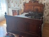a bed with a wooden headboard and foot board in the middle of a room with floral wallpaper