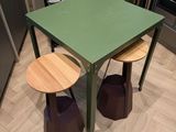 une table verte et deux tabourets dans une pièce