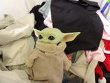 a stuffed baby yodah sitting in a pile of clothes