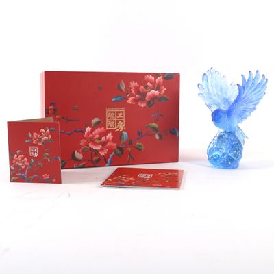 un oiseau bleu posé à côté d'une boîte rouge et d'un vase bleu