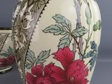 two vases with flowers painted on them sitting on a table