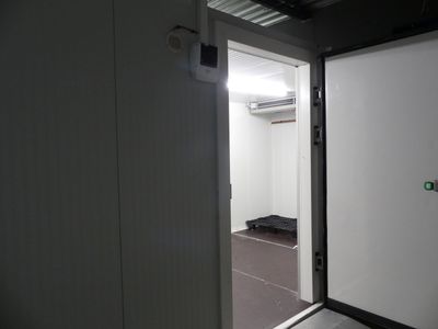 une porte blanche sur laquelle se trouve un bouton vert, dans une pièce