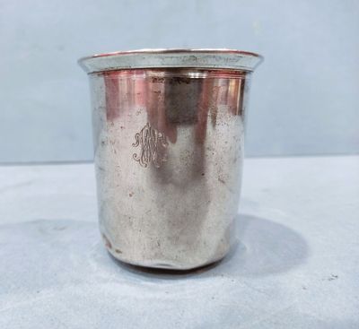 a silver cup with a handle sitting on top of a table