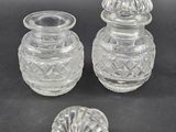 three clear glass vases and a small glass bowl on a black surface