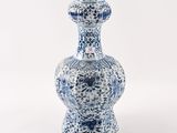 un vase bleu et blanc posé sur une surface blanche