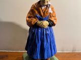 une figurine représentant une vieille femme assise sur une table