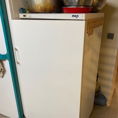 un réfrigérateur blanc sur lequel sont posés des casseroles, dans une cuisine