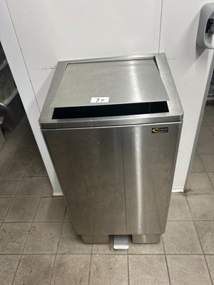 a stainless steel trash can in the corner of a bathroom