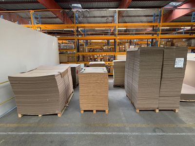 several stacks of cardboard are stacked on pallets in a warehouse