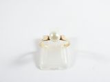 a close up of a ring with a pearl on a white surface