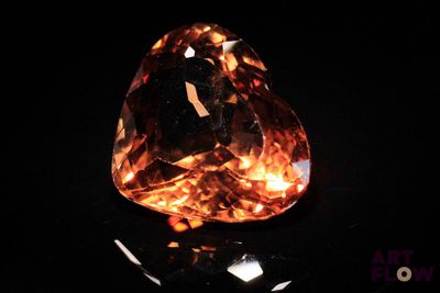 an orange diamond on a black surface with a black background