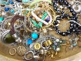 a wooden bowl filled with assorted jewelry on a table