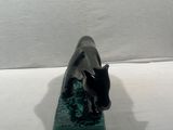 a black and green statue of a dolphin on a white surface
