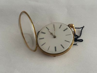 une montre de poche en or avec un cadran blanc sur une surface blanche