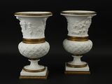 paire de vases blancs à bordure dorée, posés sur des socles