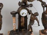 three statues of a man and a woman with a clock