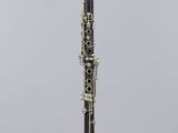 a black and white clarinet on a clear stand against a gray background