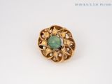une image représentant une broche en pierre verte et perles posée sur un fond blanc