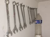 a lot of wrenches hanging on the wall next to a can of soda
