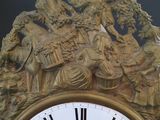 a gold clock with roman numerals on the face