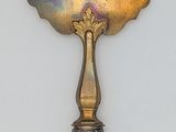 a silver spoon with a handle on a white wall