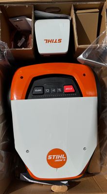 une machine orange et blanche posée à l'intérieur d'une boîte, elle-même posée sur un carton