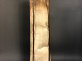 a tall wooden sculpture with a metal stand on a black background