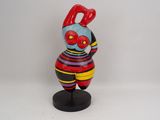 figurine of a woman in a colorful dress on a black stand