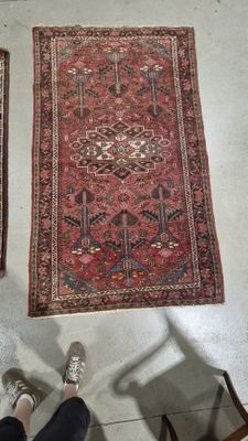 deux tapis posés à même le sol dans une pièce où une personne est assise sur une chaise